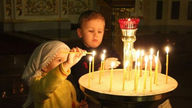 дети ставят свечи в церкви